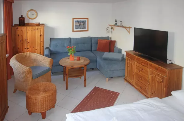 Wohnbereich mit Eckcouch, Kommode und TV